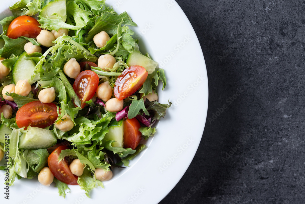 Healthy chickpea salad with tomato,lettuce and cucumber on black slate background Healthy chickpea salad with tomato,lettuce and cucumber on black slate background