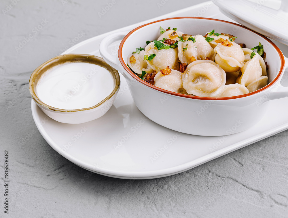 Delectable dumplings in ceramic pot on white plate Delectable dumplings in ceramic pot on white plate