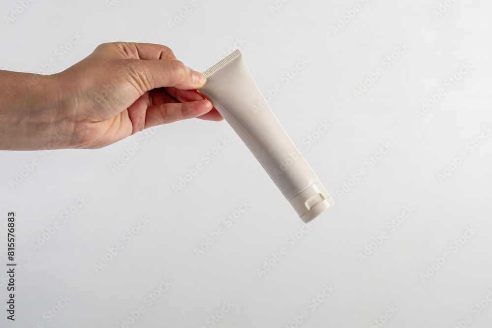 Plastic white tube for cream or lotion. Skin care or sunscreen cosmetic with hand on white background. Plastic white tube for cream or lotion. Skin care or sunscreen cosmetic with hand on white background.