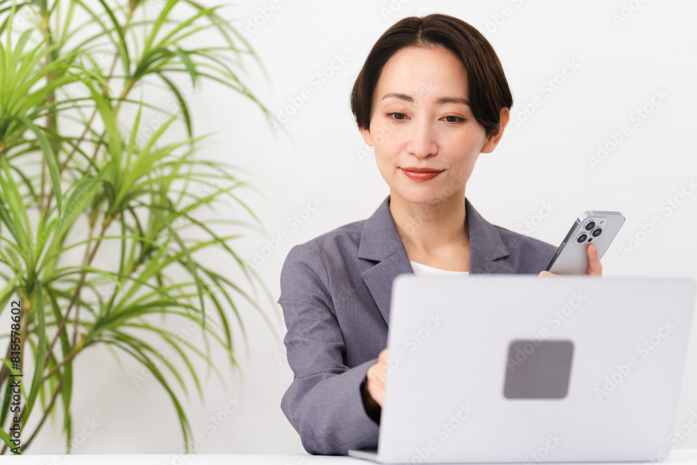 ビジネススーツを着てラップトップを操作している若い女性　ビジネスイメージ