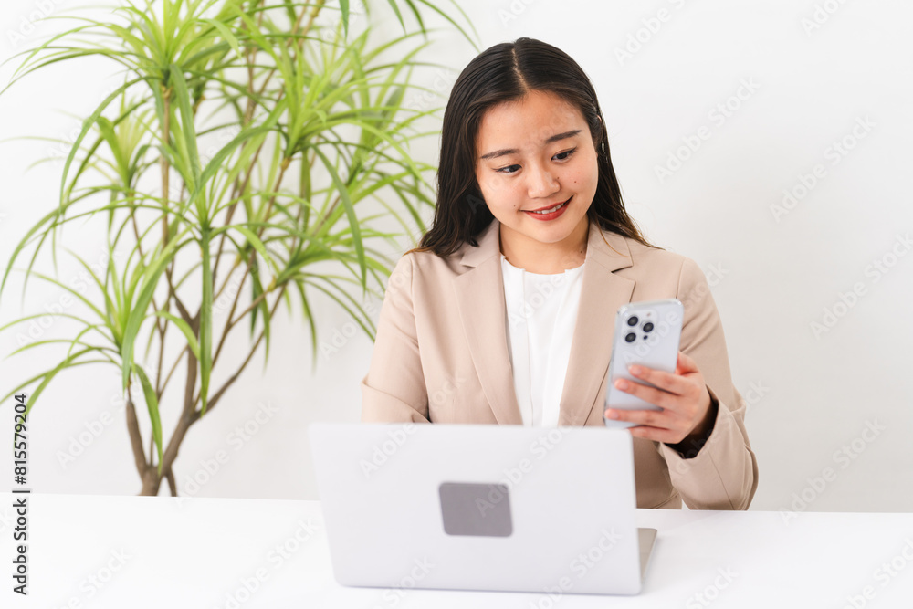 ビジネススーツを着てラップトップを操作している若い女性　ビジネスイメージ