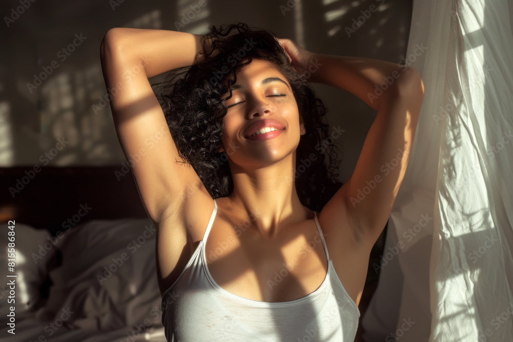 Fototapeta premium happy mixed race woman stretching in her bedroom with natural lighting. 