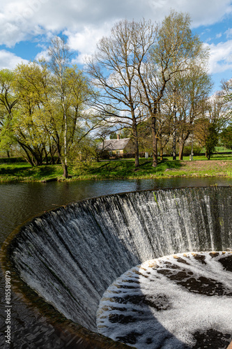 Water flows from a dam on the river. Spring in the village. Zagare, Latvia photo