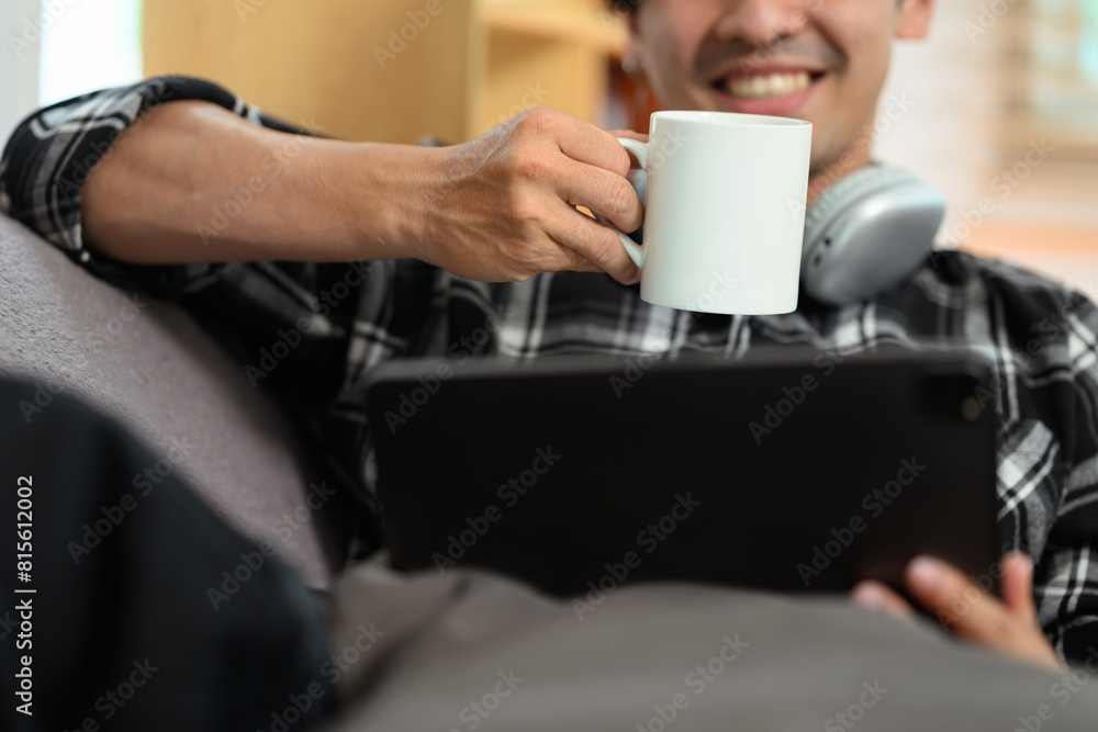 Smiling adult man drinking coffee and browsing Internet on digital tablet Smiling adult man drinking coffee and browsing Internet on digital tablet