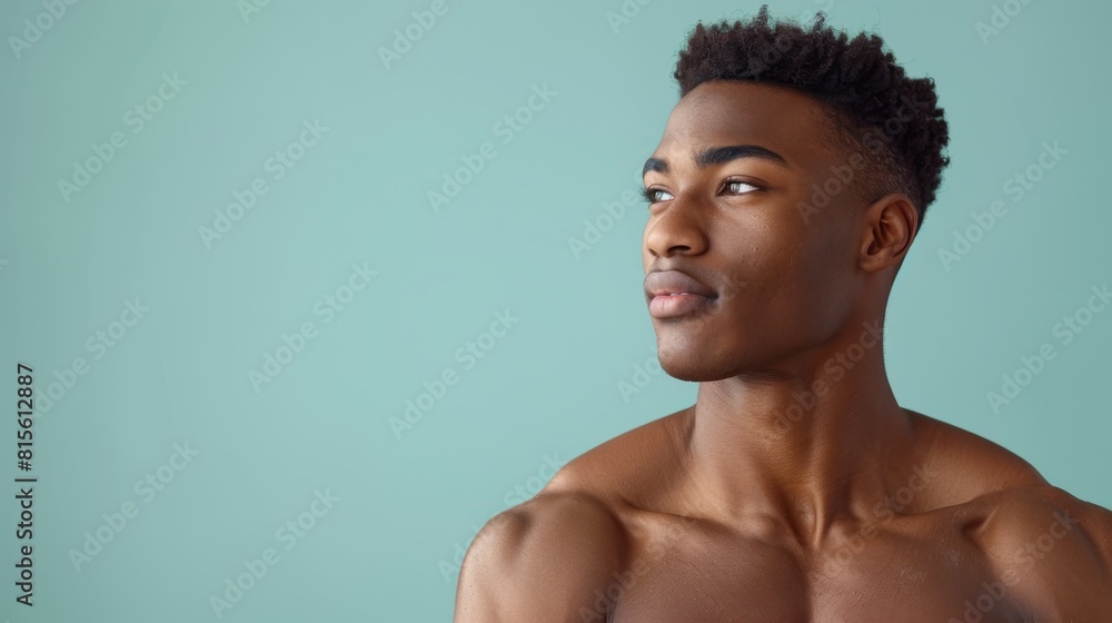 Portrait of a young muscular man with bare shoulders against a teal background, looking away thoughtfully. Portrait of a young muscular man with bare shoulders against a teal background, looking away thoughtfully.