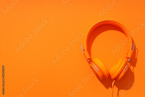 On-top, large, bright orange headphones, on a light background.