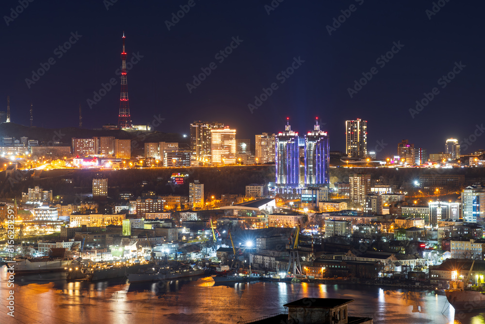 Vladivostok city, Primorsky Krai, Russia. Beautiful night city landscape. View of the Golden Horn Bay and residential areas. There are ships at the piers. A TV tower in the distance. Russian Far East. Vladivostok city, Primorsky Krai, Russia. Beautiful night city landscape. View of the Golden Horn Bay and residential areas. There are ships at the piers. A TV tower in the distance. Russian Far East.