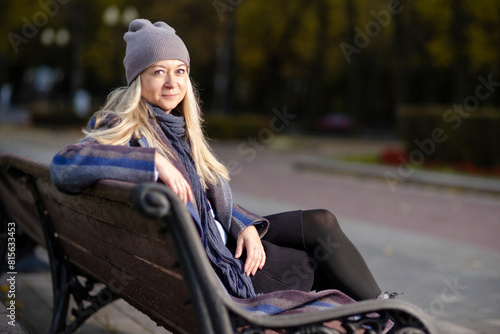 Young Woman In Park At Autumn Season Happy Free Natural Portrait Girl Breathing Deeply in Coat Sitting on Bench On Foliage in Background As Pretty Woman