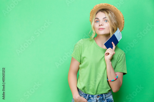 Travel Concepts. One Positive Dreaming Winsome Lovely Smiling Young Girl in Straw Hat Holding Passport with Tickets isolated Over Trendy Green