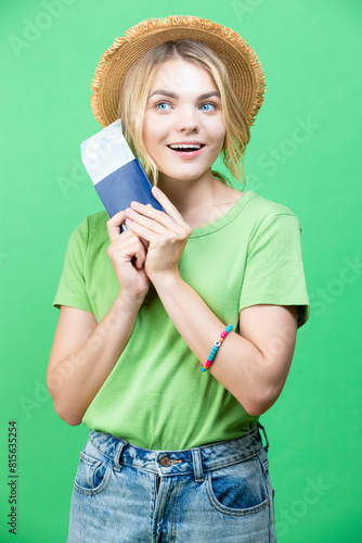 One Positive Dreaming Winsome Lovely Smiling Young Girl in Straw Hat Holding Passport with Tickets isolated Over Trendy Green