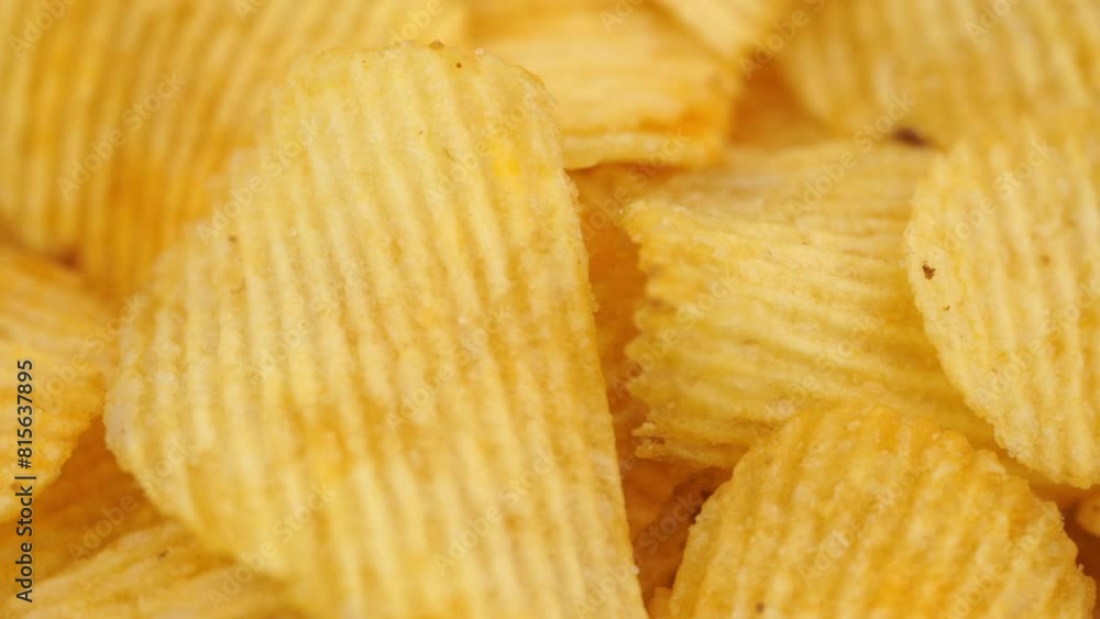 Crispy potato chips rotating in macro. Golden fried potatoes close up. Potato snack for unhealthy fast food. Crispy potato chips rotating in macro. Golden fried potatoes close up. Potato snack for unhealthy fast food.