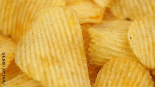 Crispy potato chips rotating in macro. Golden fried potatoes close up. Potato snack for unhealthy fast food. 