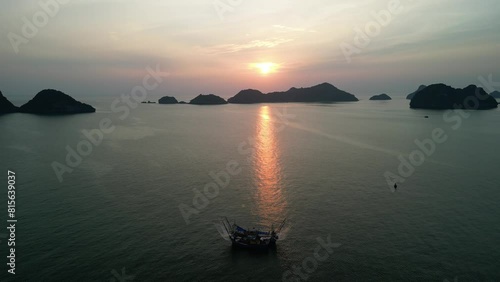 Ascending drone footage of fishing boat moored in La Han Bay in Cat Ba island at sunset, Vietnam photo