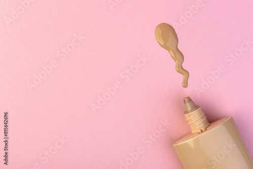 Tube of foundation on pink background. © Natallia