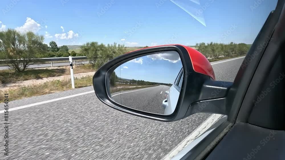 View of the rearview mirror through the window of a car driving on a highway