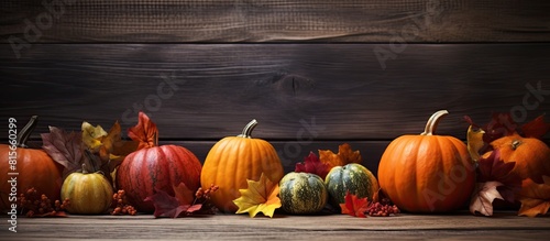 An autumnal scene with leaves and pumpkins placed on top of a rustic wooden background providing ample space for any desired text or image