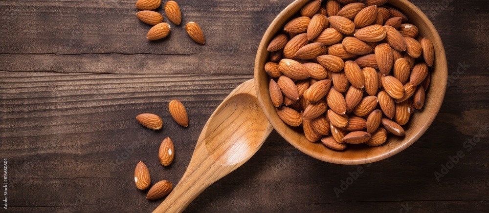 Almonds in wooden bowl and wooden spoon with brown napkin on wooden table top view for copy space Almonds in wooden bowl and wooden spoon with brown napkin on wooden table top view for copy space