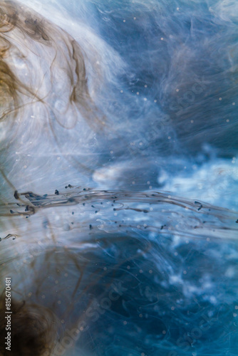 white Ink dropped into the water and photographed while in motion. Paint swirling in water.