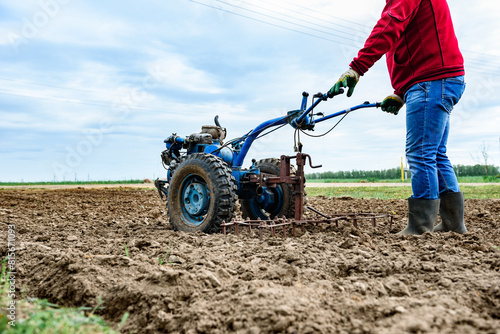 Man cultivating soil with tiller block in spring. photo