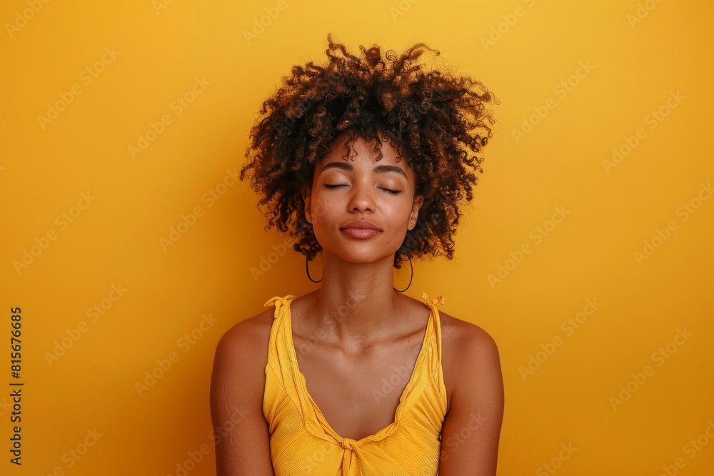 Woman with a serene expression practicing meditation, in peaceful attire against a calming yellow background