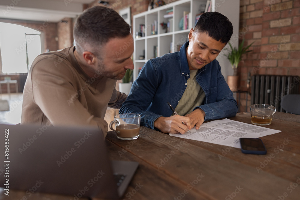 Gay couple at home signing a contract together Gay couple at home signing a contract together