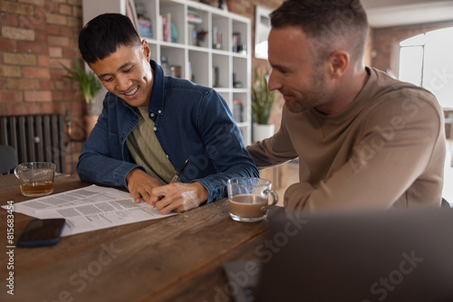 Gay couple at home signing a contract together photo