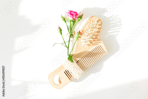 Hair dresser frame composition with pink roses and hairbrush on white background. Flat lay, top view