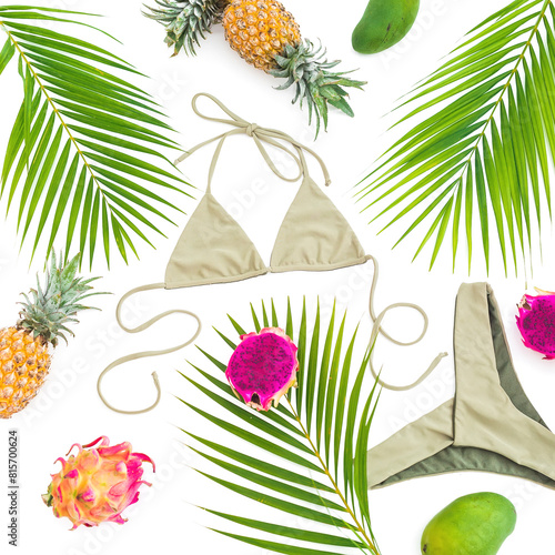 Vacation concept. Tropical fruits with palm tree leaves and bikini on white background. Flat lay, top view. © artifirsov