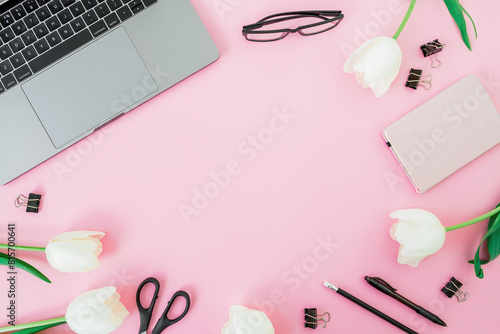 Office desk with laptop, flowers and pink diary on pink background. Flat lay. Freelance concept with copy space © artifirsov