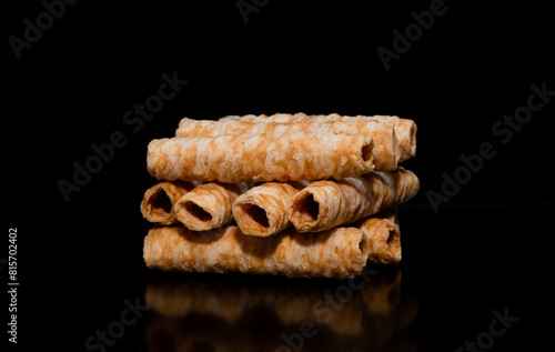 A bunch of cylinder shape waffles. Many coconut crispy roll wafers on a black background
