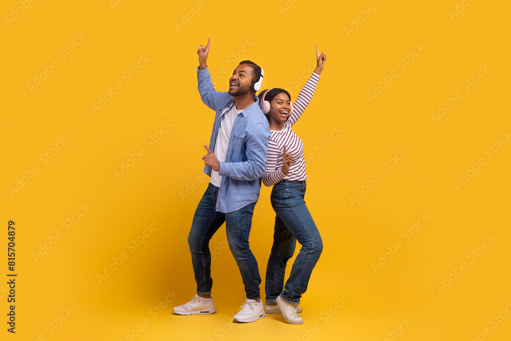 A young African American man and woman are shown mid-movement, joyfully dancing with their arms raised and big smiles on their faces, set against a vibrant yellow backdrop A young African American man and woman are shown mid-movement, joyfully dancing with their arms raised and big smiles on their faces, set against a vibrant yellow backdrop