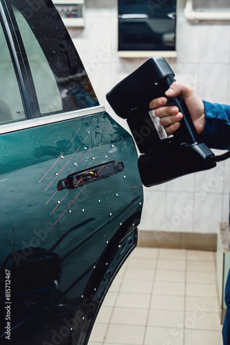 Industrial professional use handheld 3D scanner inspecting car door.