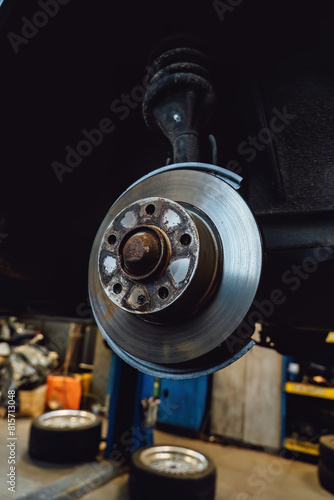 The rim is removed showing the rotor and caliper. Disc brake on car in process of new tire replacement