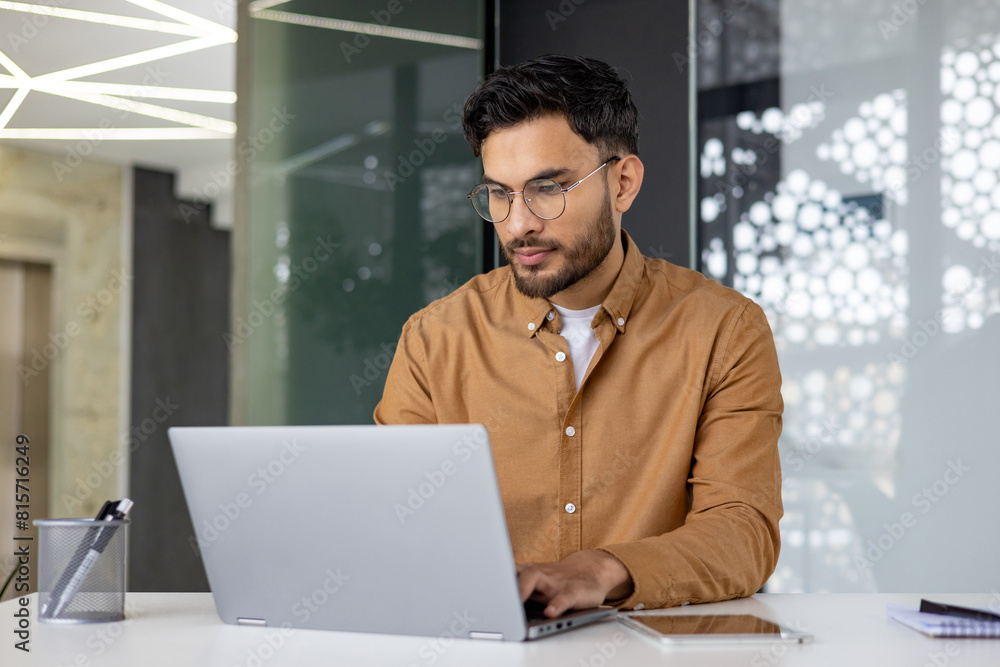 Focused professional working on a laptop in a modern office environment Focused professional working on a laptop in a modern office environment