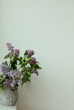 Simple compositions of lilac flowers bouquet in design vase,  white wall, template copy space.