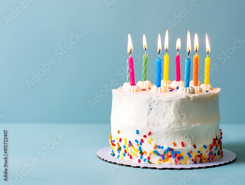 A simple white birthday cake with colorful candles on top, placed against a blue background with copy space for text or message