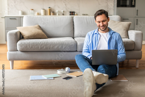 Photography A man is seated on the floor with a laptop open in front of him