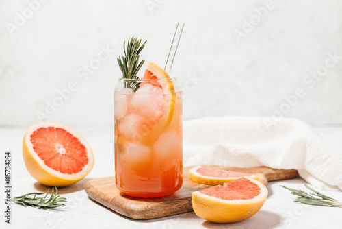 Foto Grapefruit cocktail with rosemary garnish in a glass, served on a wooden cutting board