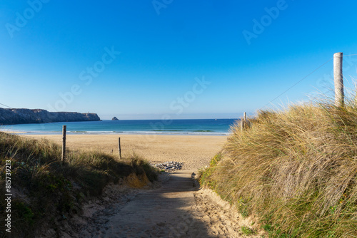 Derri  re les hautes herbes bordant le passage entre les dunes de la plage de Pen Hat  le bleu de la mer d Iroise se fond sous un ciel bleu  offrant une vue magnifique sur la pointe de Pen Hir.