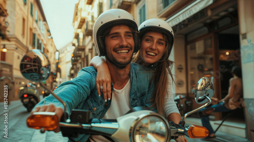 A couple young man and a woman riding a scooter together. They are both smiling and wearing helmets. The background shows a street in the city with buildings around them. Pleasure of travel © Vladimir