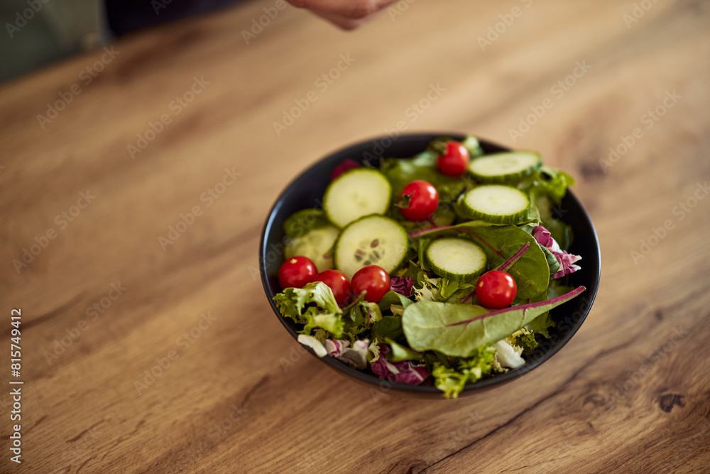 A close-up of a fresh vegetable salad served in a bowl on a wooden table A close-up of a fresh vegetable salad served in a bowl on a wooden table