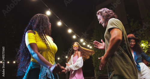 Happy multi-ethnic young people dancing in backyard at party. Portrait of African American girl and Caucasian guy having fun and moving outdoors. Beautiful females and handsome boys dance. Fun concept