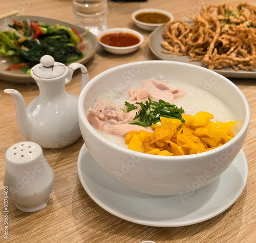 rice porridge with shredded chicken called bubur ayam served with crackers and sliced spring onion and others condiments photo