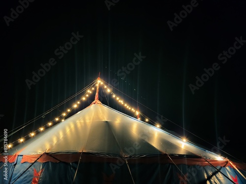 Vibrant Circus Tent Featuring Striking Blue and Red Stripes, Illuminated by Enchanting String Lights Under the Night Sky, Creating a Magical Atmosphere. Isolated on the Black Background with Copyspace