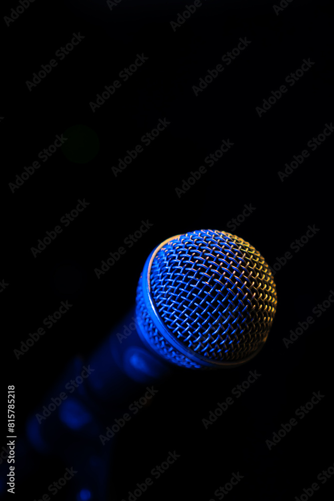 Close-up of a microphone with blue backlight in a music studio, at a concert in the dark, copy space. Vertical photo Close-up of a microphone with blue backlight in a music studio, at a concert in the dark, copy space. Vertical photo