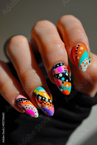 A person holding up colorful nail art with dots.