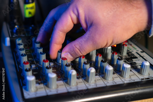 Close-up of sound mixer console in recording studio. Men's Hand Adjustment Manual Adjustment Buttons. Working mixing console in colorful background. DJ in nightclub at concert. Sound engineer