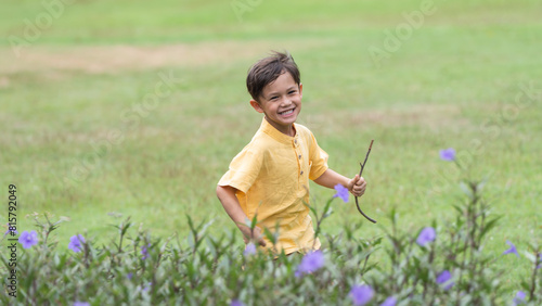 Happy little 4 year old Caucasian boy running in flowers field smiling, laughing, sunny day. Cute child boy playing outdoors in summer in nature