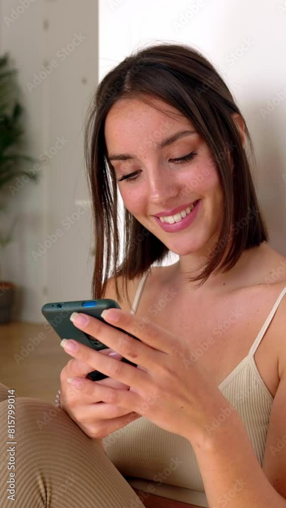 Vertical HD video of young healthy pretty woman using mobile phone while relaxing after workout exercises at home. Technology lifestyle and home workout concept. Vertical HD video of young healthy pretty woman using mobile phone while relaxing after workout exercises at home. Technology lifestyle and home workout concept.