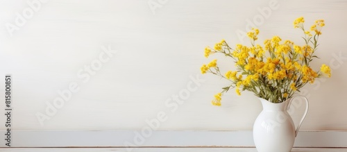 A copy space image of yellow wild summer flowers arranged in a jug on a vintage white interior © StockKing